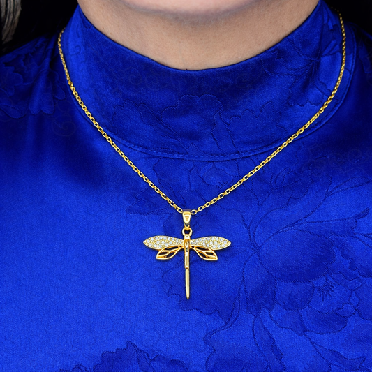 Gouden libelle ketting met witte zirkonia steentjes gedragen op blauwe achtergrond