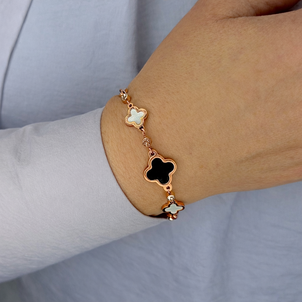 Gouden klaver armband met zwarte en witte details gedragen om de pols, elegant en luxe uitstraling