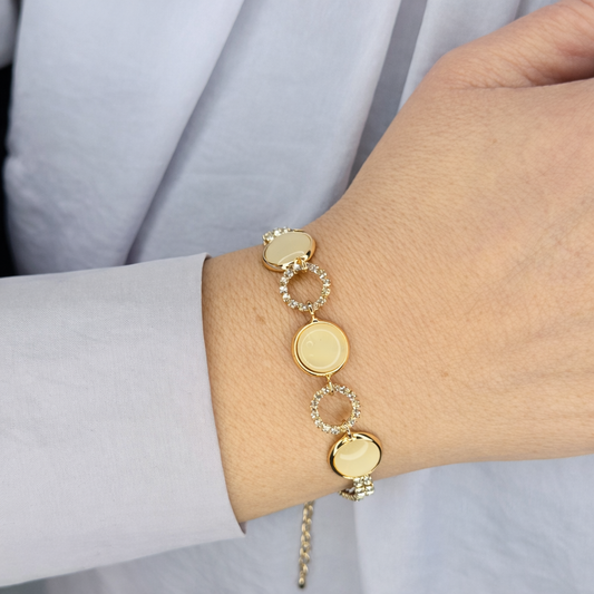 Gouden damesarmband met ronde schakels en zirkonia accenten, gedragen om de pols, close-up productfoto op lichte achtergrond.