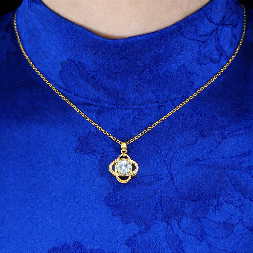 Goudkleurige ketting met wit fonkelende zirkonia hanger, gedragen op blauwe stof