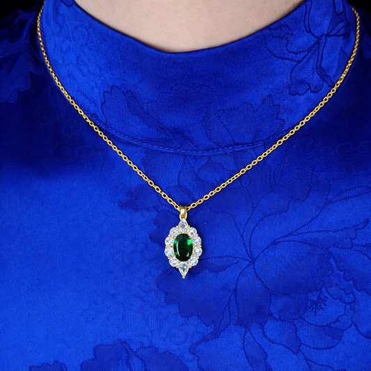Gouden ketting met groene ovale steen en witte zirkonia gedragen op blauwe jurk