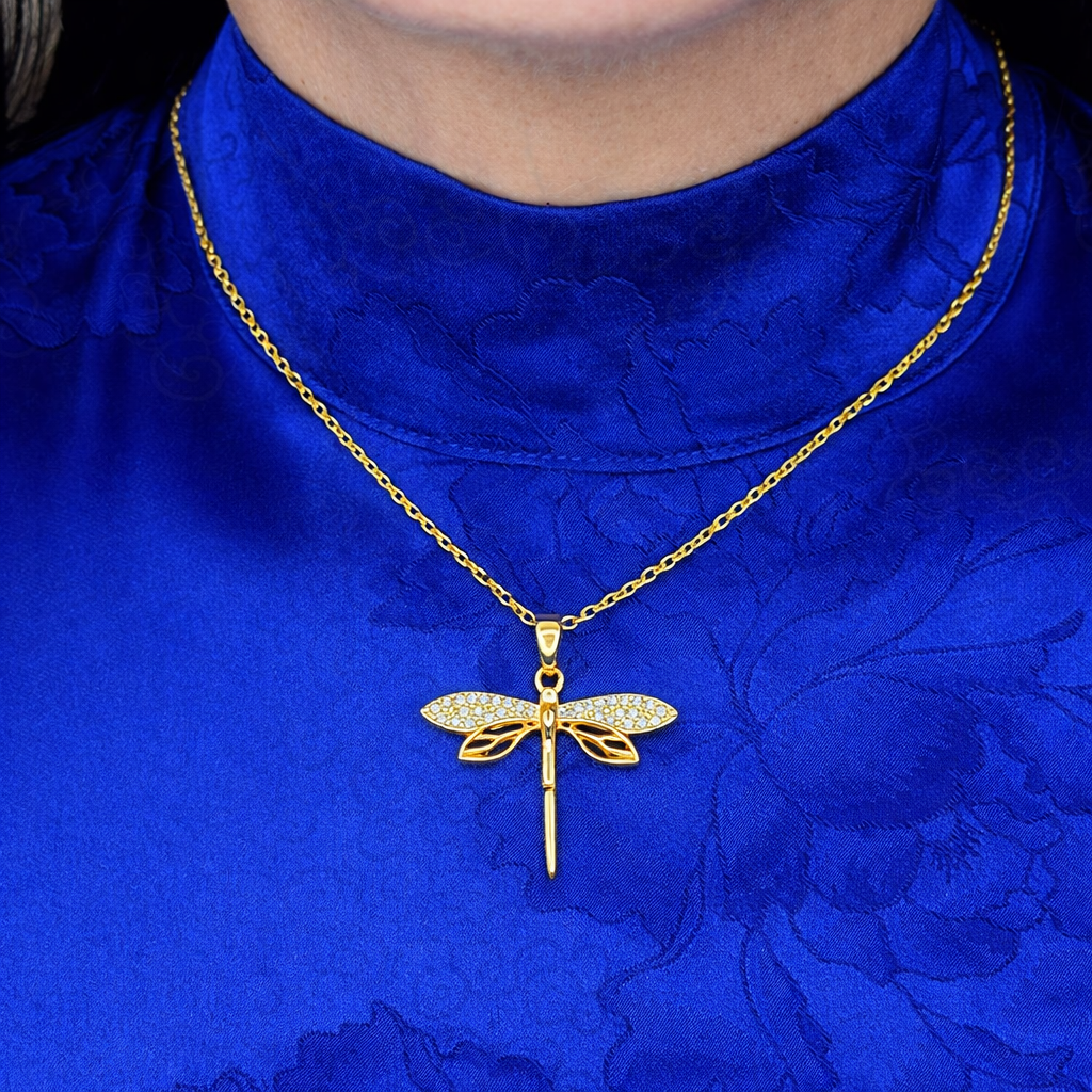 Gouden libelle ketting met witte zirkonia steentjes gedragen op blauwe achtergrond