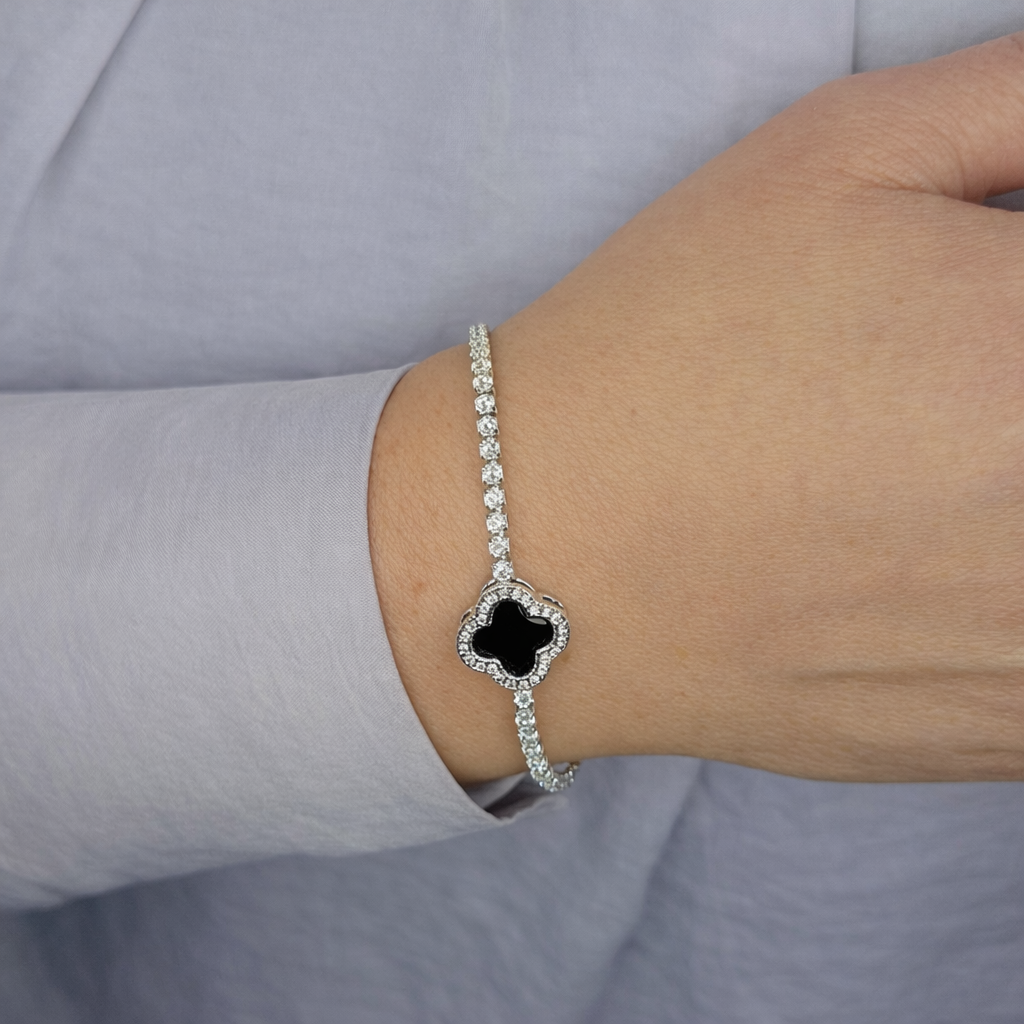 Zilveren armband met zwarte klaversteen en fonkelende zirkonia, gedragen om de pols