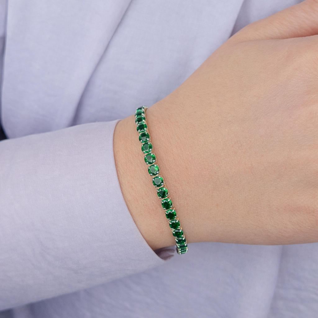 Groene stenen armband voor dames, elegante zilverkleurige zetting met fonkelende groene kristallen, gedragen om de pols.