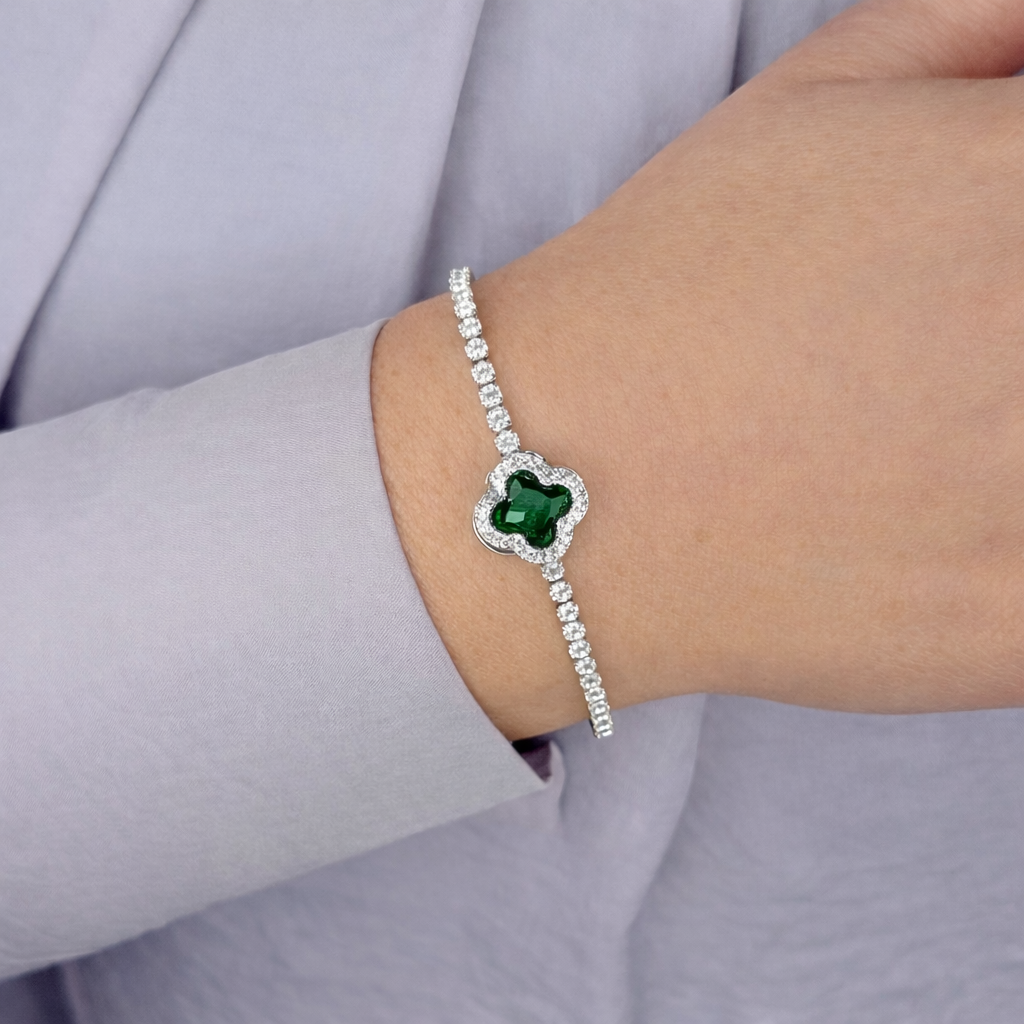 Zilverkleurige armband met fonkelende zirkonia stenen en centrale transparante steen, gedragen om de pols tegen een lichte achtergrond.