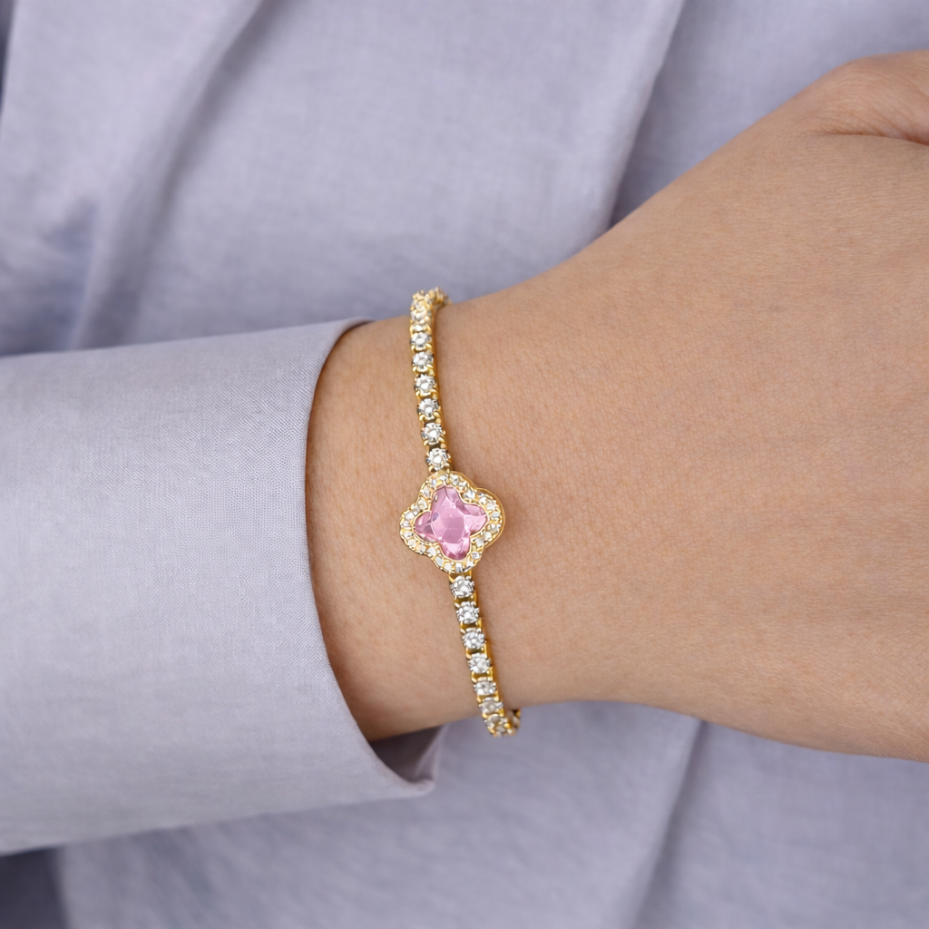 Gouden armband met roze klaversteen en fonkelende zirkonia, gedragen om de pols
