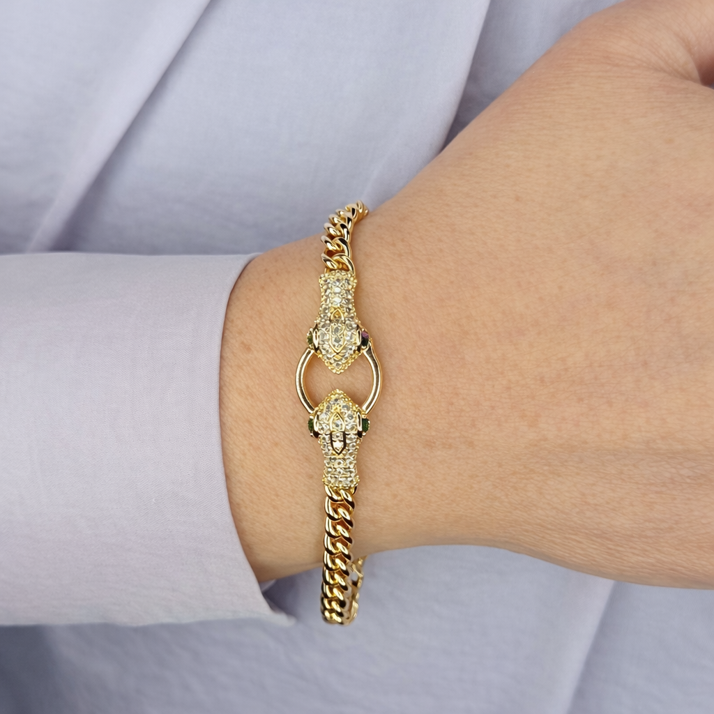 Gouden schakelarmband met luxe pavé bezette sluiting, gedragen om de pols, met verfijnde details en glanzende afwerking.