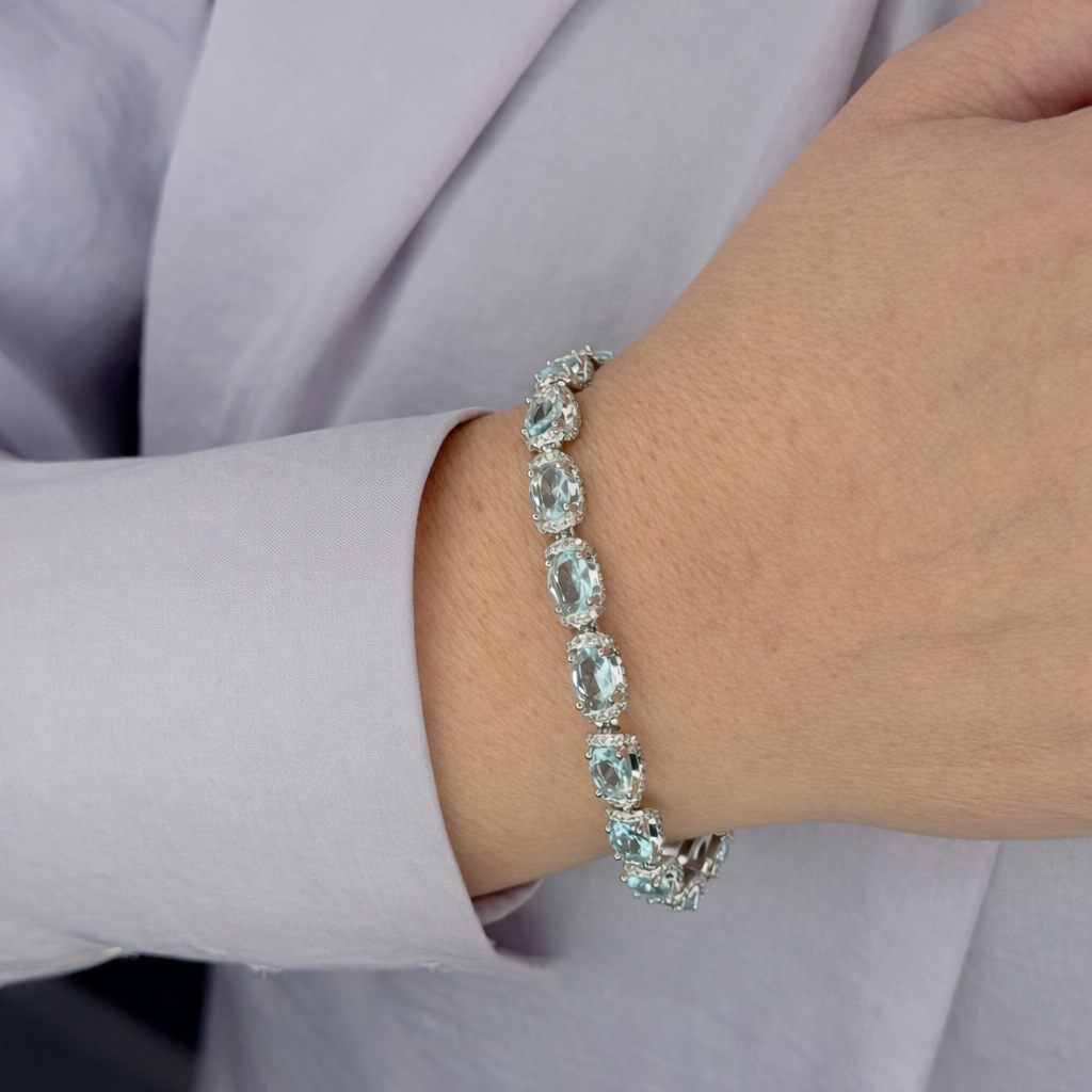 Zilverkleurige dames armband met lichtblauwe ovale kristallen, gedragen om de pols, gefotografeerd van dichtbij voor een productpagina.