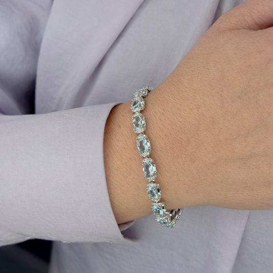 Zilverkleurige dames armband met lichtblauwe ovale kristallen, gedragen om de pols, gefotografeerd van dichtbij voor een productpagina.