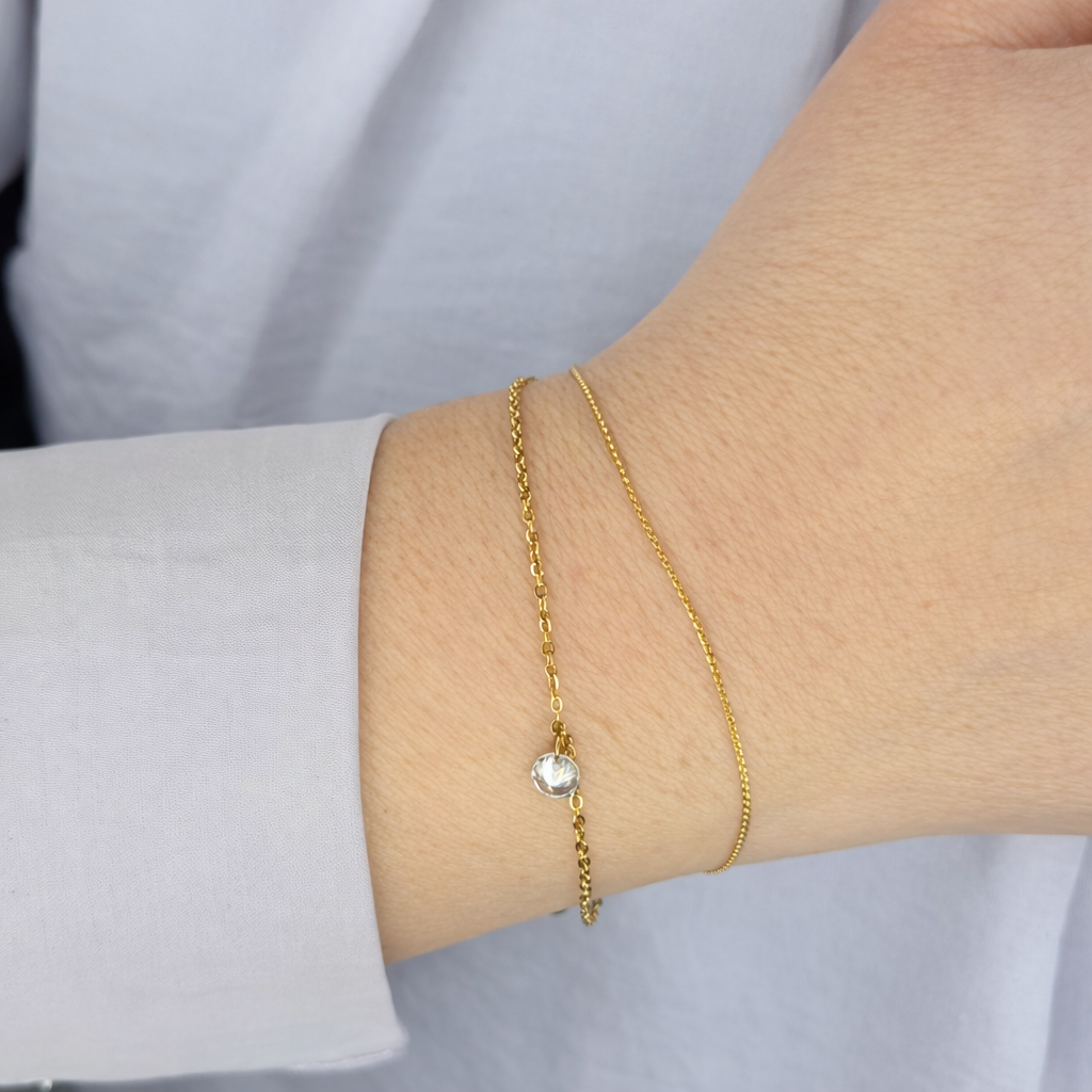 Fijne gouden armbanden voor dames met subtiele zirkonia steen, gedragen om de pols – minimalistisch en elegant design.