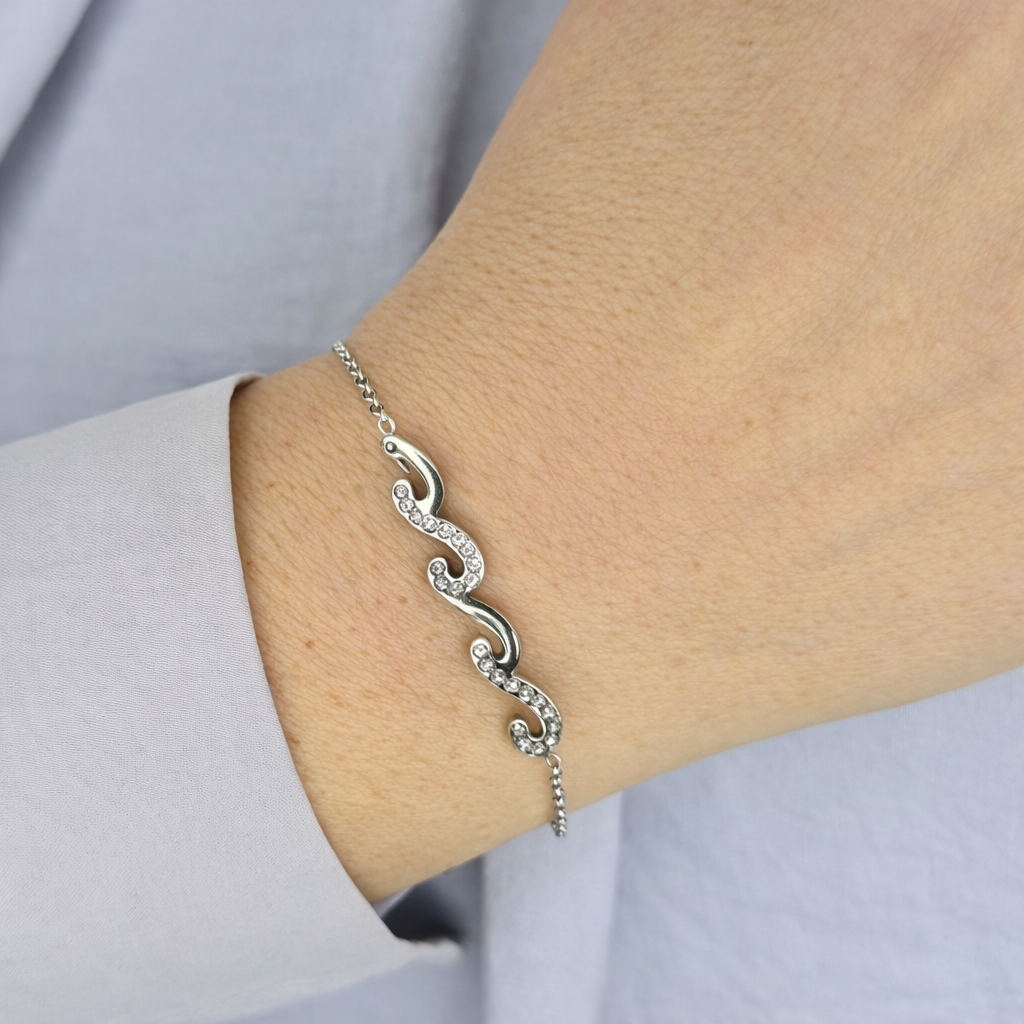 Zilveren damesarmband met golvend S-design en fonkelende zirkonia stenen, elegant gedragen om de pols.