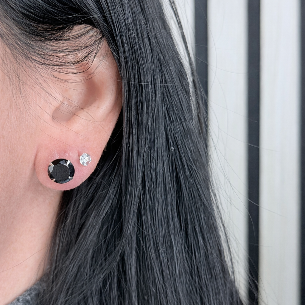 zwart zirconia oorstekers van zilver, ronde solitaire studs gedragen in het oor met natuurlijke lichtinval.