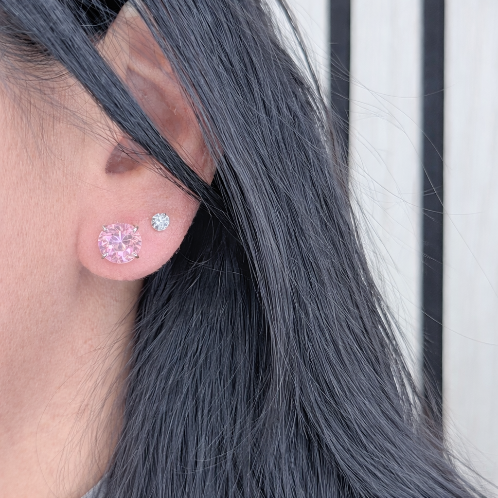 roze zirconia oorstekers van zilver, ronde solitaire studs gedragen in het oor met natuurlijke lichtinval.