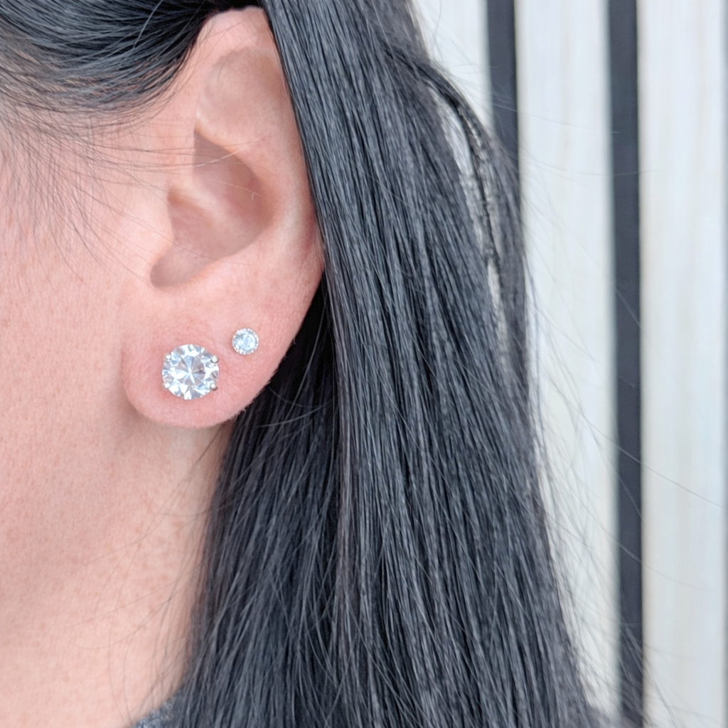 witte zirconia oorstekers van zilver, ronde solitaire studs gedragen in het oor met natuurlijke lichtinval.