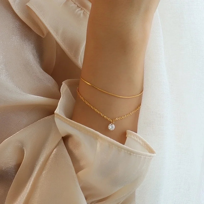 Fijne gouden armbanden voor dames met subtiele zirkonia steen, gedragen om de pols – minimalistisch en elegant design.